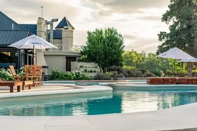 a pool with chairs and umbrellas in front of a house at Hotel Chapaqñan in Villa Rumipal
