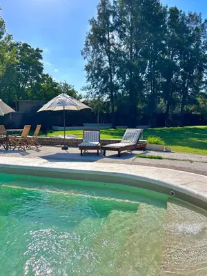 a swimming pool with two benches and an umbrella at Hotel Chapaqñan in Villa Rumipal