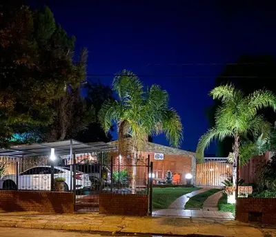 a house with two palm trees in front of it at La Morena in Villa Carlos Paz