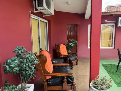 a red wall with rocking chairs in front of a house at La Morena in Villa Carlos Paz