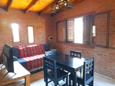 a living room with a table and a couch at Cabaña EL ZORZAL de Villa del Dique in Villa del Dique