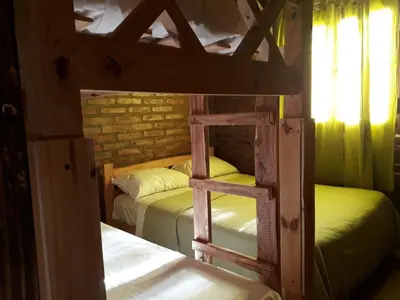 two bunk beds in a room with a ladder at Cabaña EL ZORZAL de Villa del Dique in Villa del Dique