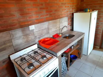 a small kitchen with a stove and a sink at Cabaña EL ZORZAL de Villa del Dique in Villa del Dique