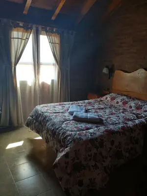 a bedroom with a bed with a blanket and a window at Cabañas Stone Hill in Santa Rosa de Calamuchita