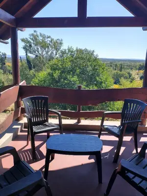 three chairs and a table on a porch with a view at Cabañas Stone Hill in Santa Rosa de Calamuchita