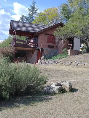 a brick house with a roof on a yard at Cabañas Stone Hill in Santa Rosa de Calamuchita