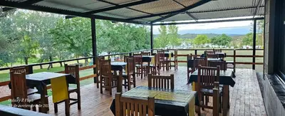 a restaurant with tables and chairs on a deck at Cabaña en el lago in Trapiche