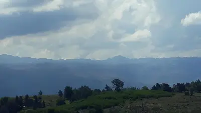 a field with trees and mountains in the background at Yacanto360 in Villa Yacanto