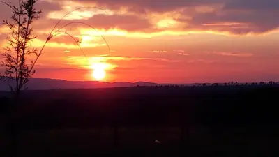 a sunset in a field with the sun setting at Yacanto360 in Villa Yacanto