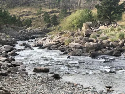 a river with rocks on the side of a mountain at Latitud 32 in Villa Yacanto
