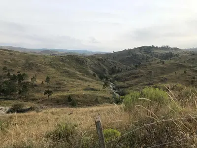 a view of a hill with a river in a field at Latitud 32 in Villa Yacanto