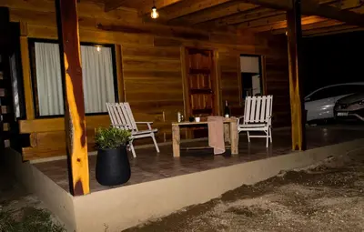 two chairs and a table on the porch of a cabin at Latitud 32 in Villa Yacanto