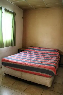 a bedroom with a bed with a striped blanket on it at La Vecindad in Cordoba