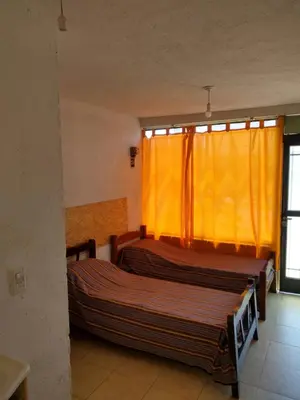 two beds in a room with an orange curtain at La Vecindad in Cordoba