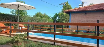 a wooden fence with a pool in front of a house at Cabañas El Sauce Mina Clavero in Mina Clavero