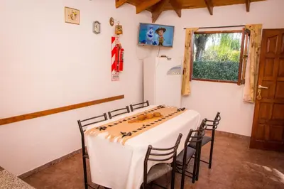 a room with a table with chairs and a refrigerator at Cabañas El Sauce Mina Clavero in Mina Clavero