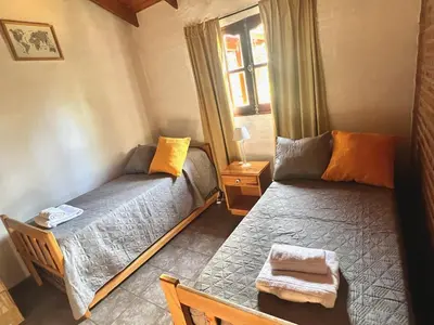 a living room with two beds and a window at Cabañas El Sauce Mina Clavero in Mina Clavero