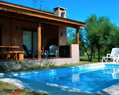 a house with a swimming pool in front of a house at Cabaña Flor de Lis in San Javier