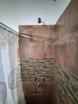 a bathroom with a shower with a stone wall at Cabañas MIS SUEÑOS in Merlo