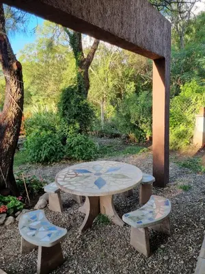 a picnic table and two stools in a garden at Cabañas MIS SUEÑOS in Merlo