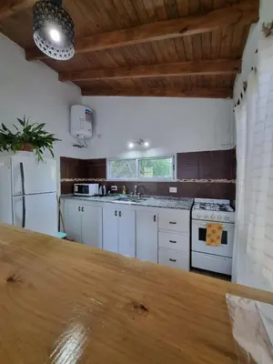 a kitchen with white cabinets and a wooden counter top at Cabañas MIS SUEÑOS in Merlo