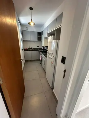 a small kitchen with white appliances and a hallway at Em Departamento Amoblado Cordoba in Cordoba