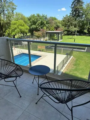 a balcony with two chairs and a table and a pool at Em Departamento Amoblado Cordoba in Cordoba