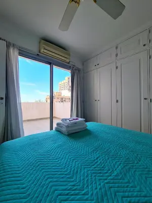 a bedroom with a blue bed with a large window at Departamento Nueva Córdoba RW in Cordoba