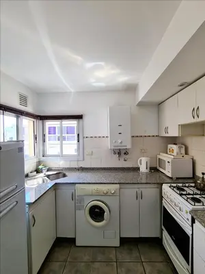a kitchen with white cabinets and a washer at Departamento Nueva Córdoba RW in Cordoba