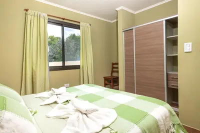 a bedroom with a green and white bed with a window at Complejo Calas in Merlo