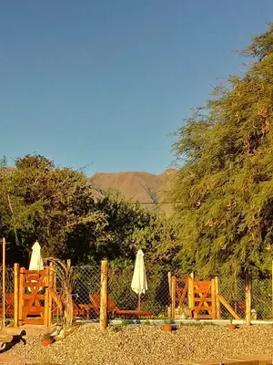 a fence with two umbrellas and two chairs at El Rincón de Alejo in Merlo