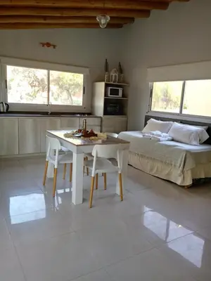 a bedroom with a bed and a white table and chairs at El Rincón de Alejo in Merlo