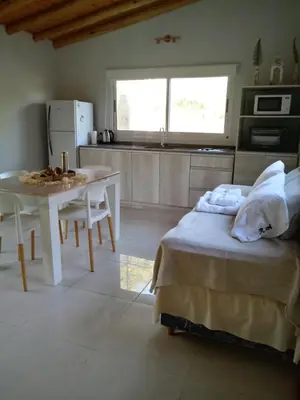 a bedroom with a bed and a table and a kitchen at El Rincón de Alejo in Merlo