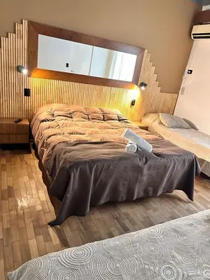 a bedroom with a large bed with a wooden headboard at Hostal de la Costa in Villa Carlos Paz