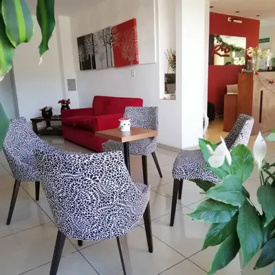 a living room with three chairs and a table at Hostal de la Costa in Villa Carlos Paz
