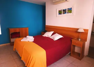 a bedroom with a bed with a red and yellow blanket at Hostal de la Costa in Villa Carlos Paz
