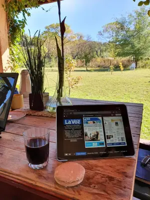 a laptop computer sitting on a wooden table with a drink at HERMOSA CASA con 4000mts de PARQUE en las SIERRAS DE CORDOBA in José de la Quintana