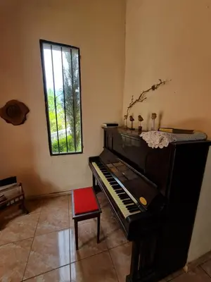 a room with a piano and a red chair at HERMOSA CASA con 4000mts de PARQUE en las SIERRAS DE CORDOBA in José de la Quintana