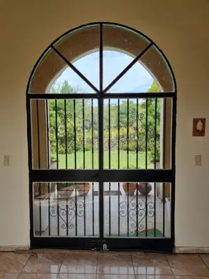 an iron gate with a view of a garden at HERMOSA CASA con 4000mts de PARQUE en las SIERRAS DE CORDOBA in José de la Quintana