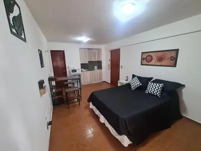a bedroom with a black bed and a kitchen at Hermoso Monoambiente en Nva Cordoba in Cordoba