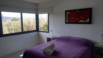 a bedroom with a purple bed and two windows at Complejo Cuatro Colores - Apart Hotel in Potrero de Garay
