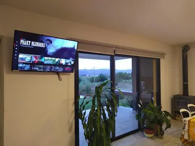 a tv on the wall of a living room with a view of a patio at Complejo Cuatro Colores - Apart Hotel in Potrero de Garay