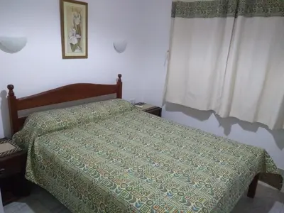 a bedroom with a bed with a green comforter at Álamos de Belén in Carpintería