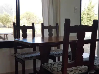 a wooden table and chairs with a table and a window at Álamos de Belén in Carpintería