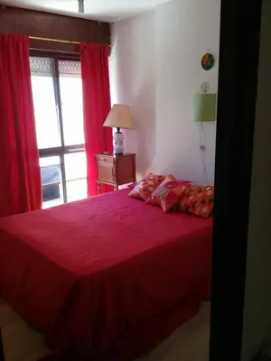a bedroom with a red bed with a window at Temporal Adry in Cordoba