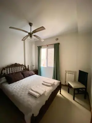 a bedroom with a bed with a ceiling fan and a chair at Punto Urbano in Villa Carlos Paz