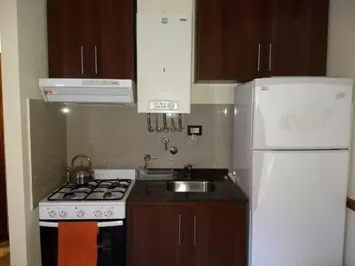 a kitchen with a stove and a white refrigerator at MIRALEJOS33K in Villa Carlos Paz