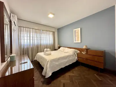 a bedroom with a bed and a dresser and a window at Amplio Piso Vintage, Terraza con Vista a Sierras in Cordoba