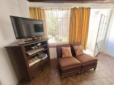 a living room with a chair and a flat screen tv at Casa Sarmiento in San Francisco del Monte de Oro