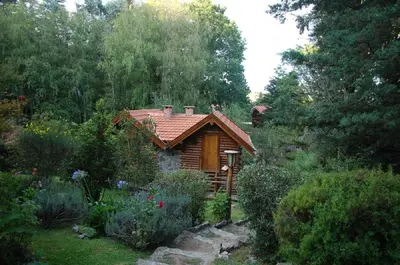 a log cabin in the middle of a garden at Cabañas Am Hang in La Cumbrecita
